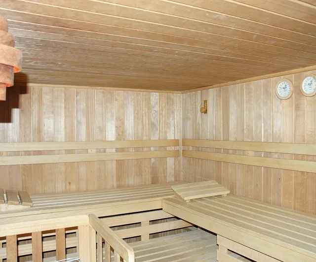 Sauna mit Holzbank und Wanduhr, die Entspannung vermittelt.